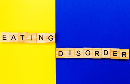 words eating disorder. Wooden blocks with an inscription on top on a yellow and blue background....