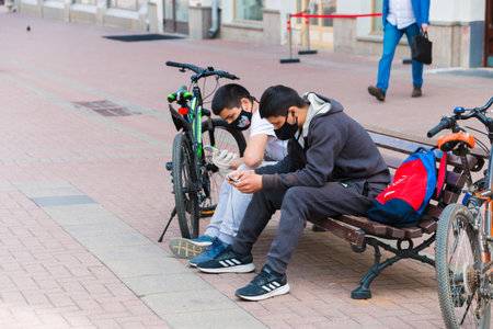 Unknown people in a mouth mask walk in the Park, sit on benches during the quarantine. Moscow, Russia, May 2020.のeditorial素材