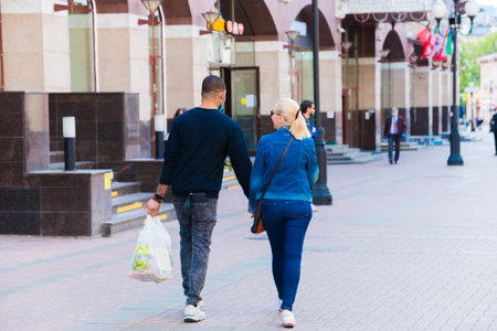 Unknown people in a mouth mask against smog air pollution from PM 2.5 walk down the street. Moscow, Russia, May 2020.のeditorial素材
