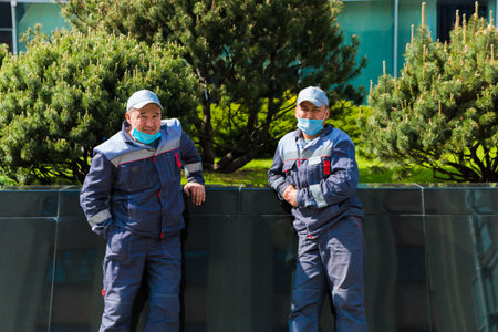 Unknown utility employees in protective masks are standing on the street during the quarantine, maintaining a distance. Moscow, Russia, May 2020.のeditorial素材