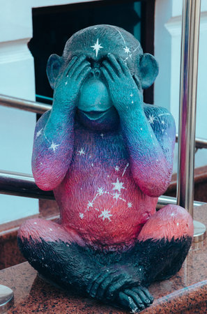 Street photo of a figure of a bright multicolored monkey with closed eyes of unusual color depicts...