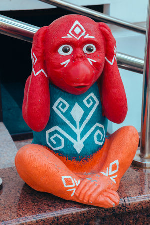 Street photo of a figure of a bright colored monkey holding a head of unusual color depicts various emotions. Moscow. Russia. June 2020.のeditorial素材