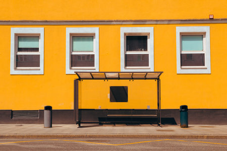 City bus stop in front of a bright yellow building, street photo. Selective focus.の写真素材