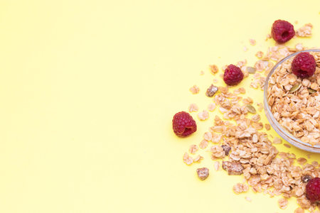 Crispy muesli with raspberry dry Breakfast isolated on yellow background selective focus, top view.の写真素材