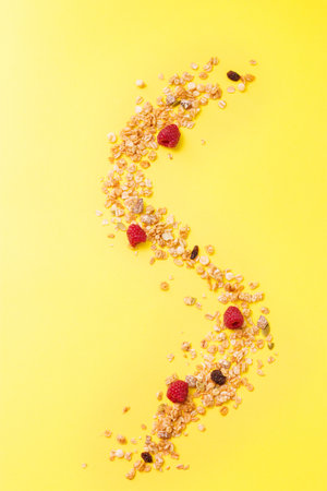 Crispy muesli with raspberry dry Breakfast isolated on yellow background selective focus, top view.の写真素材