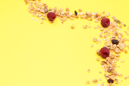 Crispy muesli with raspberry dry Breakfast isolated on yellow background selective focus, top view.
