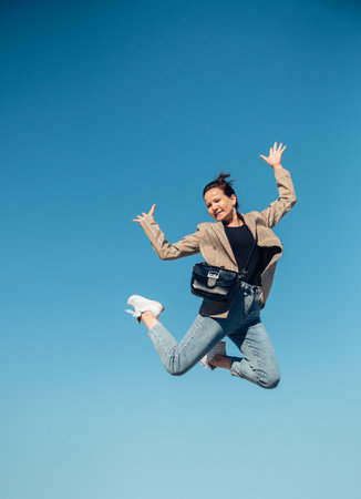 jump in the air. A girl in full height jumps in the air having fun on a bright blue turquoise background of the summer sky color. Selective focus.の写真素材