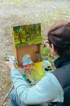 Plein. Men draw picturesque pictures of an Apple orchard in nature under natural light to show a...
