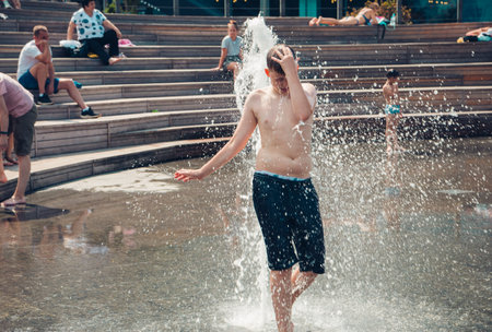 Hot summer weather, unknown small children bathe in the city fountain in the park. Moscow, Russia, July 2020.のeditorial素材