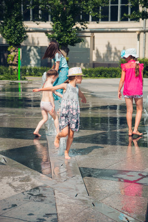 Hot summer weather, unknown small children bathe in the city fountain in the park. Moscow, Russia, July 2020.のeditorial素材