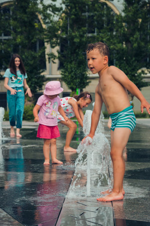 Hot summer weather, unknown small children bathe in the city fountain in the park. Moscow, Russia, July 2020.のeditorial素材
