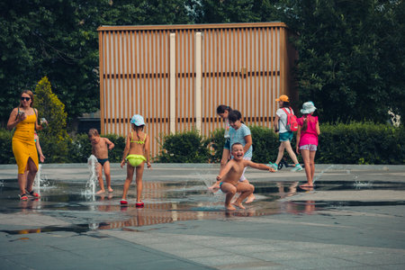Hot summer weather, unknown small children bathe in the city fountain in the park. Moscow, Russia, July 2020.のeditorial素材