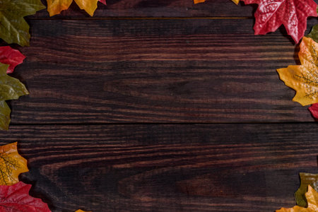 dark wooden background with maple leaves along the edges. space for notes