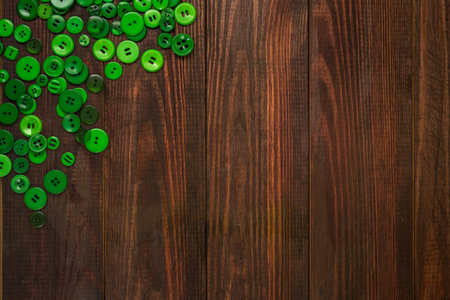 Green buttons of various sizes are scattered in the corner of the wooden background with room for...