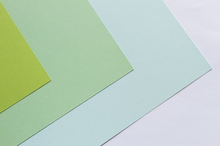 Sheets of paper of green shades lie on the table with corners in one direction.の写真素材