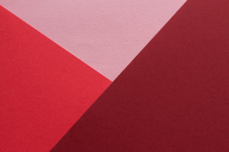 Paper in three shades of red lies on the table, creating a geometric compositionの写真素材