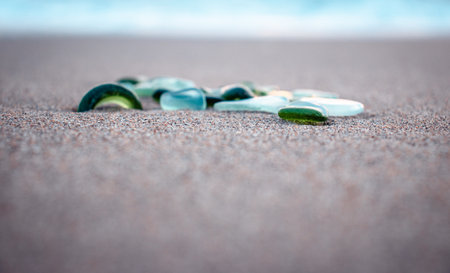 Sand beach and glass stones concept photo. Glass stones from broken bottles polished by the sea. Front view photography with blurred background. High quality picture for wallpaper, travel blogの写真素材
