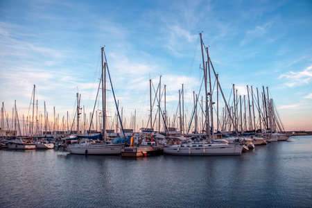 Yachts in the port, sailboat harbor in the evening photo. Beautiful moored sail yachts in the sea...