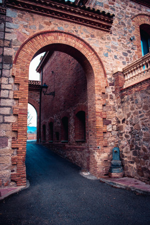 The exterior of an old farm concept photo. An arch through which you can see the backyard an old stone building. Seen shady corner. Old brick wall texture background. High quality picture for wallpaper, articleの写真素材