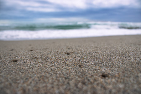 Close up sea sand beach with foam and waves photo. Sand beach surface with selective focus....