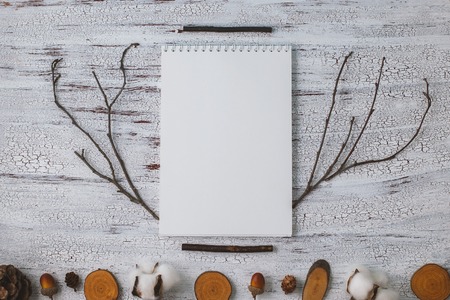 Empty notebook on a wooden background, decorated with twigs and acorns. place for textの写真素材