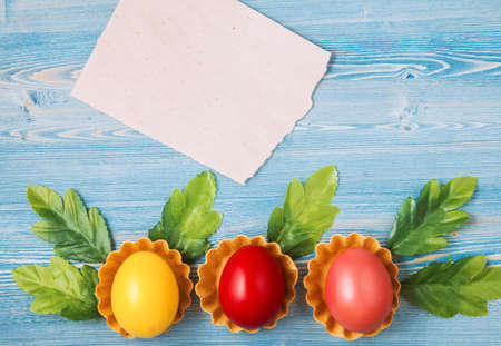 Easter multicolored eggs on a blue wooden background with a notebook Background for a postcard, Easter concept, space for text.の写真素材