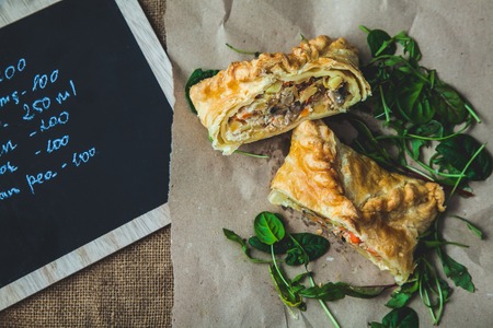 puff pastry stuffed with meat, carrots, potato pie, decorated with rucola, on a dark background Background for postcard. Menu, restaurant, recipe concept, served in.の写真素材