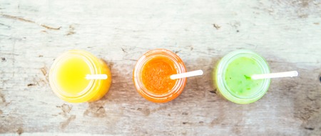 freshly squeezed fruit juice, smoothies yellow orange green on a dark wooden background Copy space. Flat lay Banner conceptの写真素材
