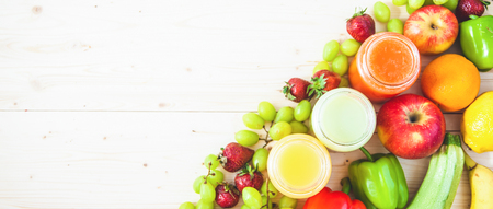 freshly squeezed fruit juice, smoothies yellow orange green blue banana lemon apple orange kiwi grape strawberry on a light wooden backgroundの写真素材
