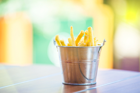 appetizing french fries in a decorative bucket on a wooden table.の写真素材