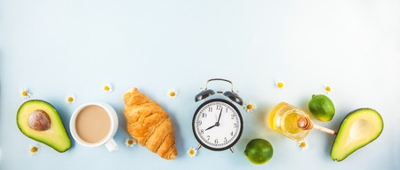 morning breakfast ,coffee in a white cup Croissant Avocado Awakening with an alarm clock Cheerful, healthy breakfast fresh Copy space Banner concept Flat layの写真素材