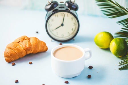 morning coffee in a white cup Croissant Lime on a light background Wake-up with an alarm clock Breakfast cheerfulness, a healthy breakfast freshness Close- upの写真素材