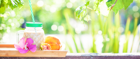wooden tray with coffee, fruit on a background of green foliage Bannerの写真素材