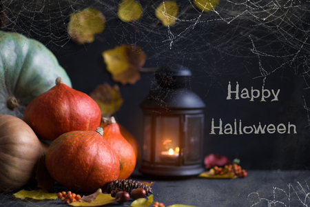 Halloween concept Orange pumpkins, a lantern with candles and foliage on a dark background with a cobweb.の写真素材