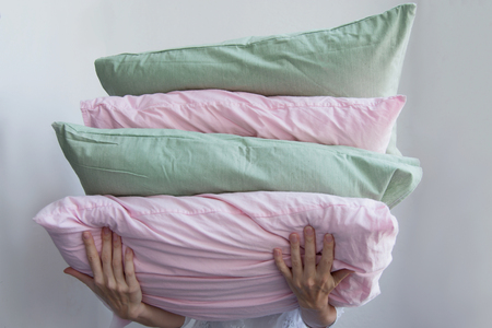 Women's hands hold many multi-colored pillows On a white backgroundの写真素材