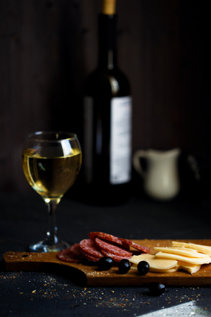 Charcuterie, cheese, salami, olives and a glass of wine on a dark table Close upの写真素材
