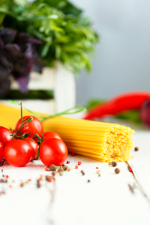 Cherry, tarragon, spaghetti, chili pepper, basil, spices Ingredients for cooking pasta. Food background on a white table Menu and restaurant conceptの写真素材