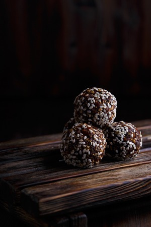 Healthy energy organic vegetarian bites with nuts, dates, honey and sesame on a dark wooden background.の写真素材