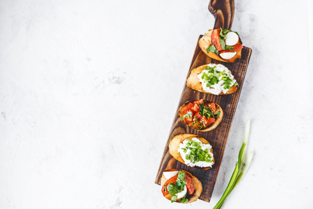 several types of italian bruschetta with tomatoes, mozzarella and herbs on a wooden board on a light background Copy space Top viewの写真素材