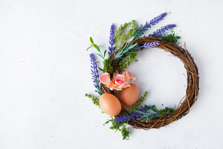 Easter concept. Bright spring flowers, wreath with easter eggs on a light background Copy space Top...