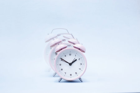 Pink ringing alarm clock on blue background Copy space