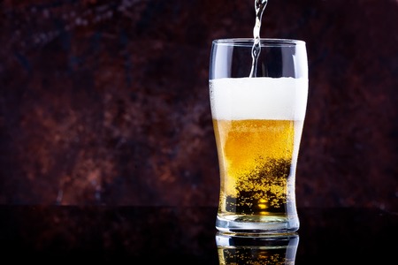 glass of beer with foam on a dark backgroundの写真素材