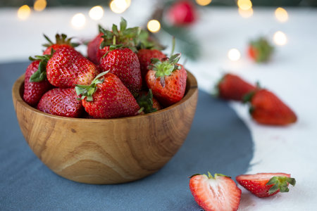 ripe strawberries in a wooden bowl on a white table on a summer background