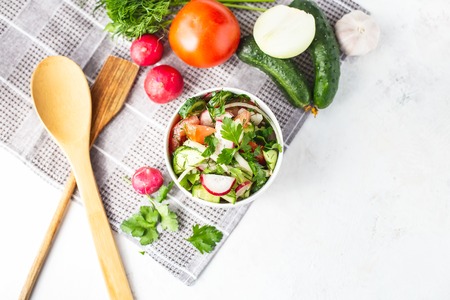 vegetarian salad of spring vegetables. tomatoes, cucumber, radish, onions. Dietary dish on a bright table. Copy space Top viewの写真素材