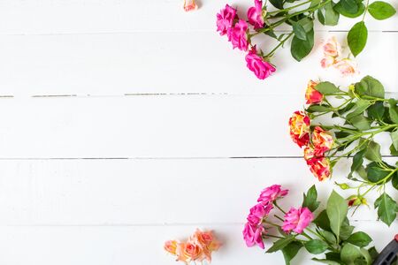 Flower frame with pink roses on wooden white background Wedding, birthday concept Postcard Top view copy space Flat layの写真素材