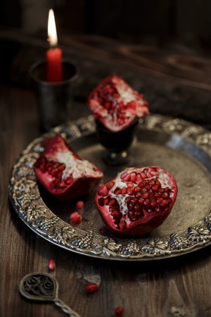 Pomegranate peeled on a silver plate, on a dark wooden table. Pomegranate seeds Rustic styleの写真素材