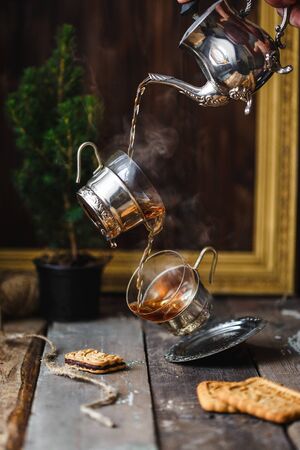 flying cups in pouring hot tea from teapot on a wooden background. Levitation. Rustic Country style Verticalの写真素材