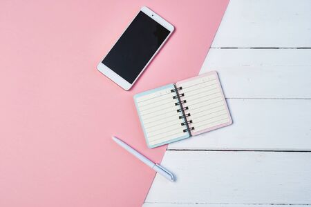 Mockup Flat lay composition with smartphone and notepad on a white and pink background. Desktop with copy spaceの写真素材