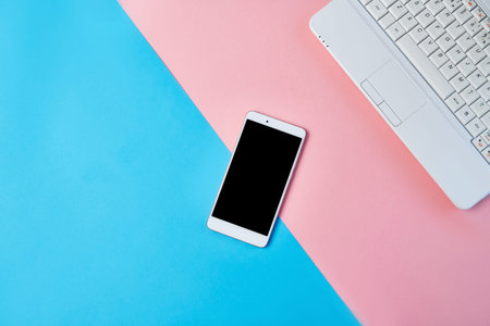 Mockup Flat lay composition with smartphone and laptop on a blue and pink background. Desktop with...