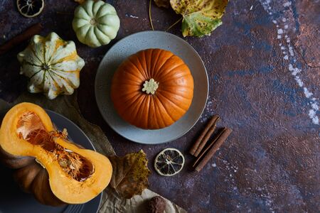 Pumpkin on a plate. Autumn cozy background with leaves, vanilla. Dark background Top viewの写真素材